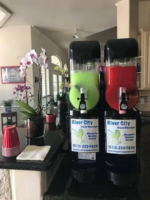 Lime and strawberry margaritas in a machine on a kitchen counter