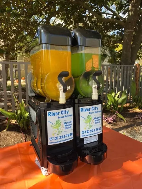 Mango and lime margarita machine on an orange party table outdoors
